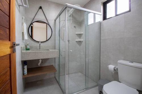 ein Badezimmer mit Dusche, Waschbecken und Spiegel in der Unterkunft Casa Em Milagres 03 suítes - 300m da Praia in Tatuamunha