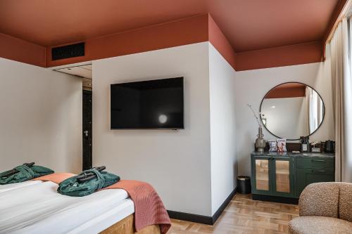 a bedroom with two beds and a tv on the wall at Hotel Fratelli in Karlstad