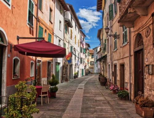 an empty street with an umbrella and chairs and buildings at Casa Valle Verde in Brugnato