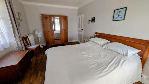 a bedroom with a large white bed with a wooden headboard at Le chalet des apiculteurs in Folles