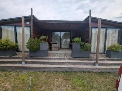 une maison avec deux plantes en pot sur une terrasse couverte dans l'établissement Magnifique Chalet, à La Teste-de-Buch