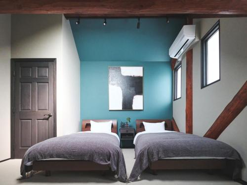 a bedroom with two beds and a blue wall at Little Deer by SANA in Tateyama