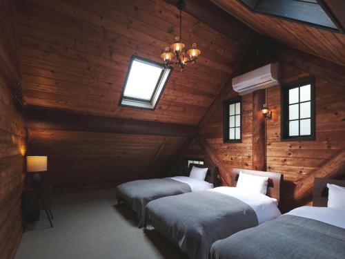three beds in a room with wooden walls and windows at Little Deer by SANA in Tateyama