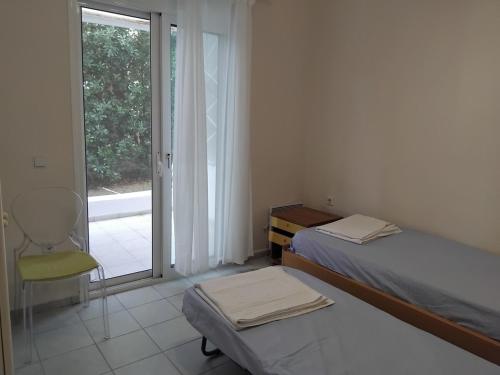 a bedroom with a bed and a chair and a window at Spacious apartment Nantia's apartment in Hanioti