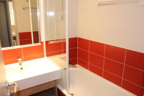 een badkamer met een bad, een wastafel en een spiegel bij Résidence Britania Clés Blanches in La Tania