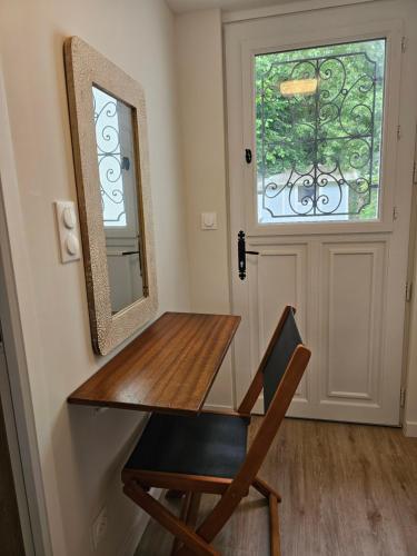 un miroir et une table en bois et une chaise devant une porte dans l'établissement Le Domicile adoré chez Béa, à Villers-sur-Mer