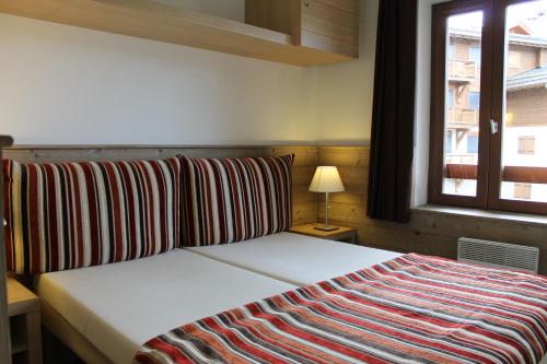een slaapkamer met een bed met een gestreepte deken erop bij Résidence Britania Clés Blanches in La Tania