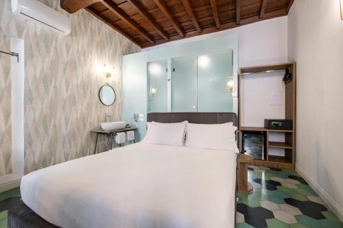 Un dormitorio con una gran cama blanca y un espejo. en 19 Steps Trevi, en Roma
