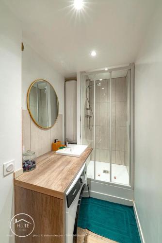 une salle de bain avec un lavabo, une baignoire et un miroir dans l'établissement Le cocon savoyard, à Chambéry