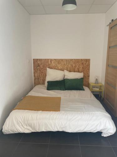 a bedroom with a large bed with two green pillows at Chez Ambre et Lulu - Appartement centre ville avec piscine in Millau