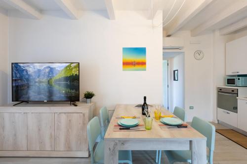 a dining room with a table and a tv at Conca d'Oro Apartments, appartamento 5 e 6 in Arco