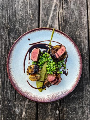a plate of food with meat and peas on a wooden table at Barley Mow in Burnley