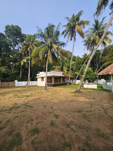 a house with two palm trees in a field at RiverSoul Villa in North Paravur