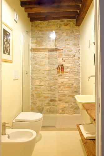 a bathroom with a white toilet and a stone wall at Casa del Moro in Mercato Saraceno