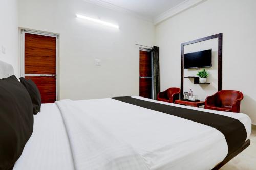 a bedroom with a white bed and two red chairs at Hotel O Ayushman in Jabalpur