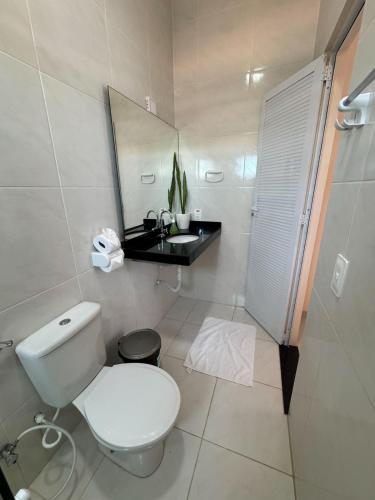a bathroom with a toilet and a sink and a mirror at Pousada dos Corais in Mundaú