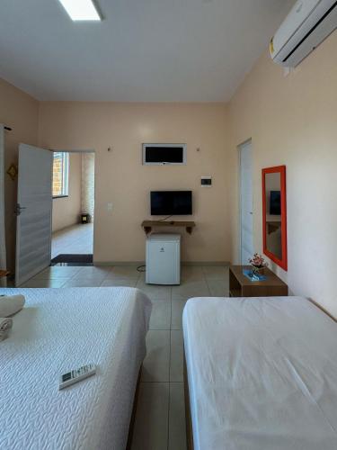 a bedroom with two beds and a tv on the wall at Pousada dos Corais in Mundaú