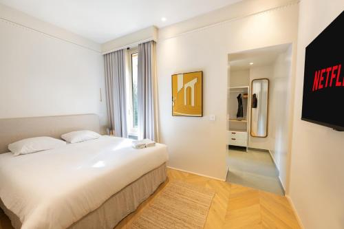 une chambre avec un lit blanc et une télévision dans l'établissement 3mn Monaco - Joli appartement rénové - DK, à Beausoleil