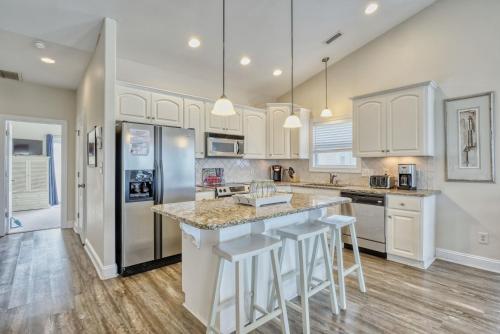 a kitchen with white cabinets and a large island with bar stools at Sea Star Village 212 in Surf City