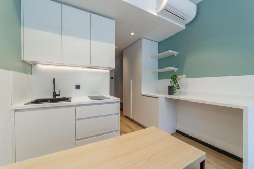 a kitchen with white cabinets and a wooden table at River Stay Apartments in Tallinn