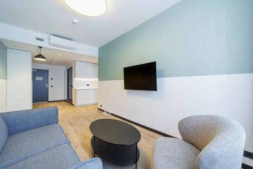 a living room with a couch and chairs and a tv at River Stay Apartments in Tallinn