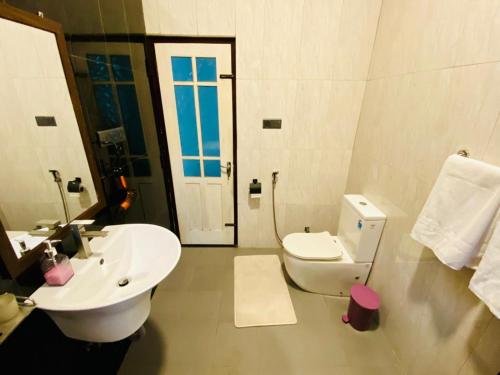 Un baño blanco con lavabo e inodoro. en The Cottage Ambuluwawa, en Gampola