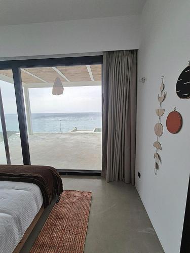 a bedroom with a bed and a view of the ocean at The Cliff in Melínta