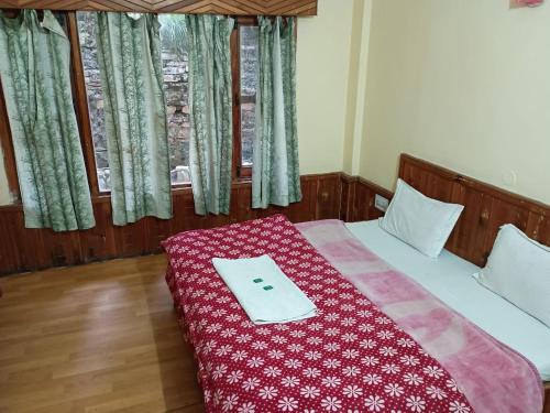 a bedroom with a bed with a red blanket on it at Moti classic deep forest in Kasol