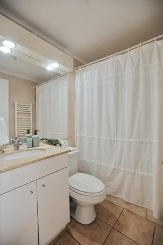 a bathroom with a toilet and a white shower curtain at Hotel Boutique Trinidad in Viña del Mar