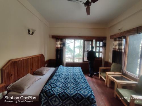 a bedroom with a bed and a person looking out the window at Moti classic deep forest in Kasol