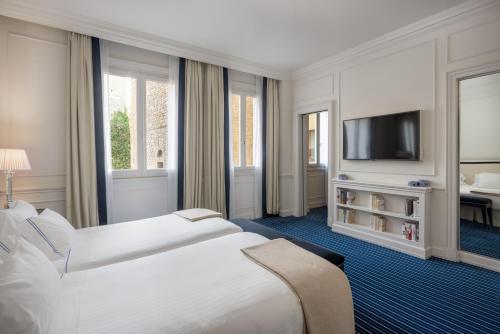 a hotel room with two beds and a flat screen tv at Hotel Lungarno - Lungarno Collection in Florence