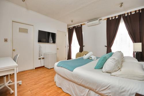 a bedroom with a large white bed and a desk at Hotel Boutique Trinidad in Viña del Mar