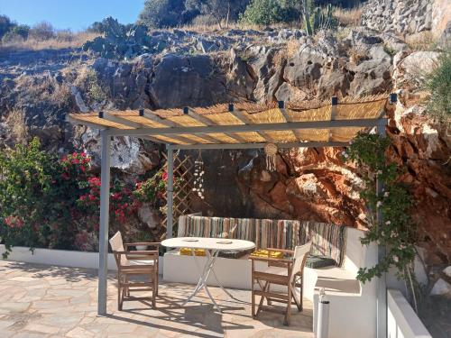 een terras met een tafel en stoelen onder een pergola bij Kamares View (Γαλήνη) in Ayeranós