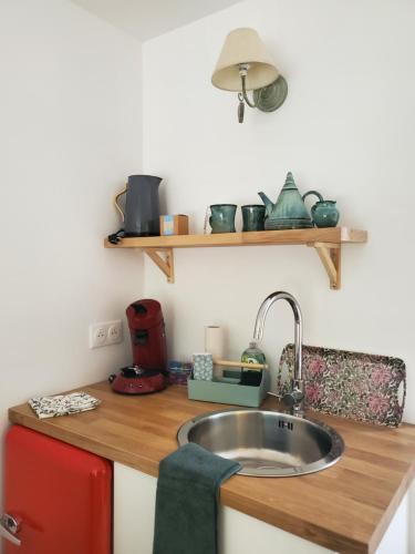 a kitchen with a sink and a red refrigerator at Le Jardin des Papillons, gîte et chambre d'hôtes à Saint Fraimbault in Saint-Fraimbault