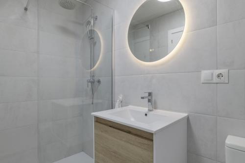 a white bathroom with a sink and a mirror at La Casa de Emilie in Conil de la Frontera