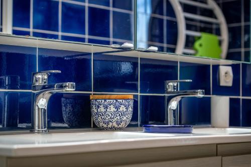 un lavabo de salle de bain avec deux robinets et un mur en carrelage bleu dans l'établissement Belle maison jardin piscine près Avignon, à Villeneuve-lès-Avignon