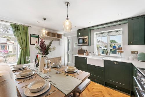 a kitchen with green cabinets and a wooden table at Gorgeous 3 Bedroom, 225 year old cottage in Portishead