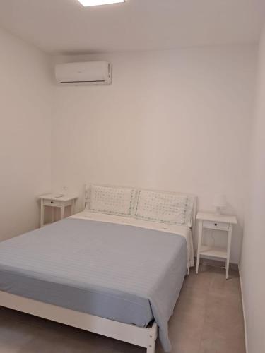 a white bedroom with a bed and two tables at Agriturismo Tenuta La Siesta in Gallipoli