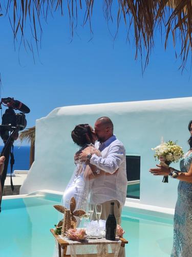 a bride and groom kissing at their destination wedding at ELLI TROPiCAL LUXURY SUITES SUNSET-INFINITY POOL- SEA SIDE-NEAR CENTER PARKING in Mikonos