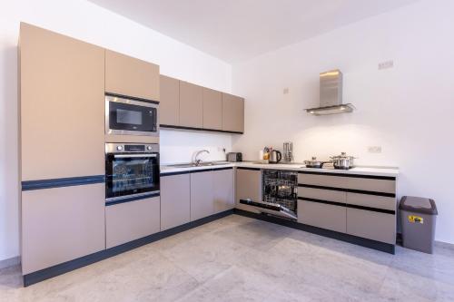 a large kitchen with white cabinets and appliances at Seaside Serenity 5 - few mins walk to the beach by QuickTrips in Is-Sellum