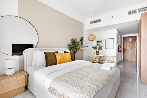 a white bedroom with a large bed and a table at Bright Boho Loft near Yas F1 Circuit & Airport in Abu Dhabi