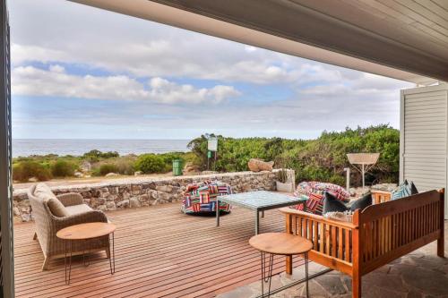 a patio with a table and chairs and the ocean at Lady Serenity - unwind in the hot tub in Kleinmond