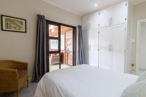 a bedroom with a white bed and a window at Lady Serenity - unwind in the hot tub in Kleinmond