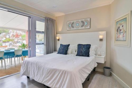 a bedroom with a large white bed with blue pillows at Lady Serenity - unwind in the hot tub in Kleinmond