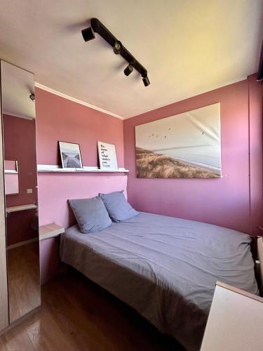 une chambre avec un lit avec un mur violet dans l'établissement T2 cosy avec parking, à Dieppe