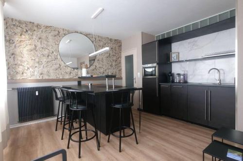 - une cuisine avec un îlot noir et un miroir dans l'établissement T2 cosy avec parking, à Dieppe