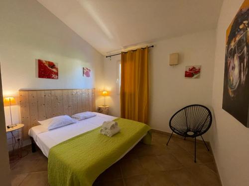 een slaapkamer met een bed met een groene deken en een stoel bij Villa Immortelle, Piscine, SPA, 500m plages et commerces in Lecci