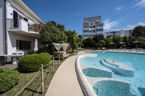 a swimming pool with chairs and a building at Villa Carlotta Jesolo Lido in Lido di Jesolo