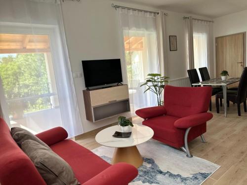 a living room with two red chairs and a tv at Apartmány Silvia in Dunajská Streda