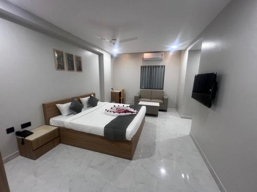 a bedroom with a bed and a couch and a television at Hotel Bhavans Elite in Rajiv Gandhi International Airport